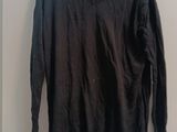 a black sweater hanging on a hanger on a wall