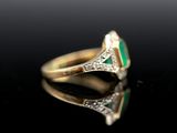 an emerald and diamond ring on a black surface