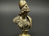 un buste en bronze représentant un homme coiffé d'un casque, posé sur un socle