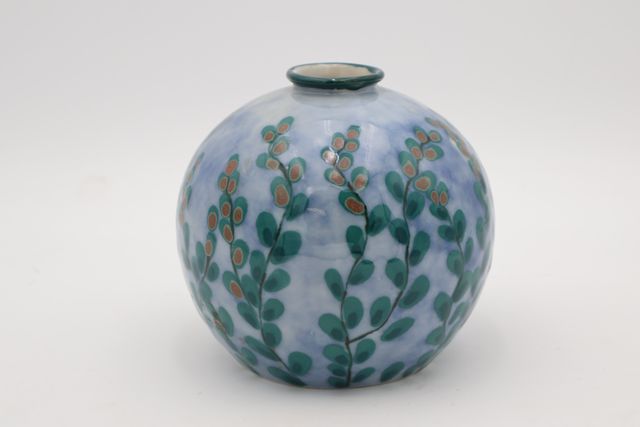 THARAUD. Limoges. Vase boule à décor de feuillages sur fond laite...