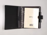 an open notebook with a black cover sitting on top of a white table