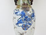 a blue and white vase on a table with a lamp on top of it