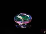 a close up of a pink and green diamond on a black surface