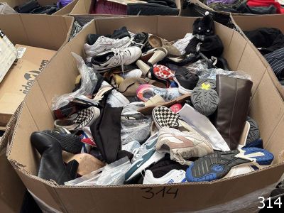 plusieurs paires de chaussures dans une boîte en carton posée sur le sol