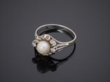 a white pearl and diamond ring on a black surface
