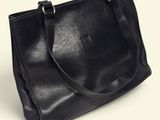 a black leather tote bag sitting on top of a white surface