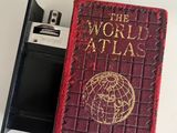 a small red book with a pen in it next to a cell phone