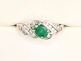 gros plan d'une bague avec une pierre verte et des diamants