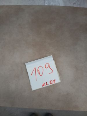 un morceau de papier posé par terre, sur lequel est collé un autocollant