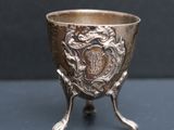 une coupe ancienne en argent posée sur un socle, sur une table