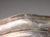 a silver vase with a curved handle on a table