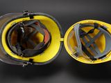 two yellow hard hats sitting on top of each other on a black surface