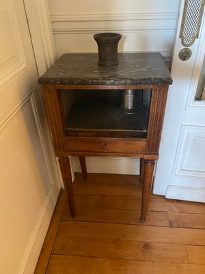une petite table sur laquelle se trouve un pot, dans un coin de la pièce