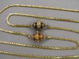 a gold chain that has two beads attached to it