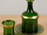 un verre vert à bord doré posé sur une table en bois