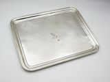 an old silver tray on a white table with a small piece of food in it