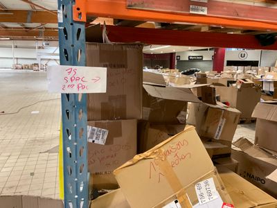 de nombreux cartons posés à même le sol dans l'entrepôt