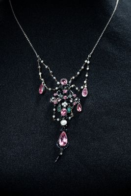 a woman wearing a necklace with pink and green stones
