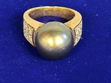 un gros plan d'une bague ornée d'une perle sur un fond bleu
