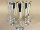 quatre verres à vin en argent sont alignés sur une table
