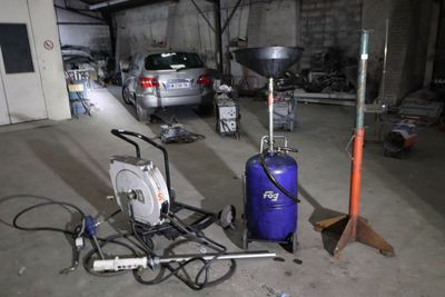 Les véhicules sont garés dans un garage où se trouvent de nombreux outils et équipements