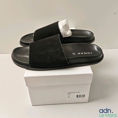 Les chaussons noirs sont posés sur une boîte blanche.