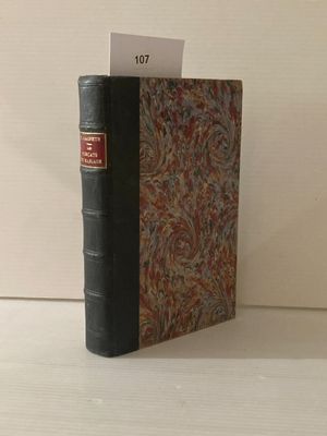 un livre noir à la couverture rouge posé sur une table blanche
