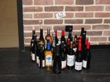 de nombreuses bouteilles de vin posées par terre, près d'un mur de briques