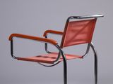 a red leather chair with chrome frame and arm rests against a gray background