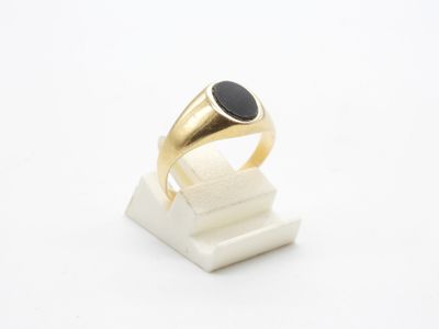 Gros plan sur une bague en or ornée d'une pierre noire