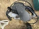a chainsaw that is laying on the ground next to a pair of shoes