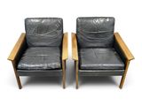 pair of black leather lounge chairs with wooden arms and arms