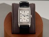 a watch that is on a wooden stand on a table