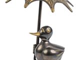 a statue of a duck with an umbrella on a stand
