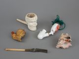 a small collection of miniature objects including a pipe, a fish, a shell, and a brush