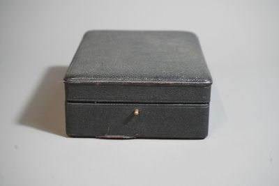 une petite boîte noire posée sur une surface blanche