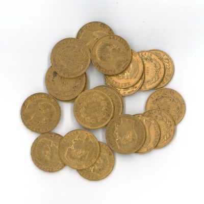 quelques pièces d'or posées sur une surface blanche, sur fond blanc