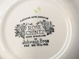 a close up of a plate with a rose chintz on it