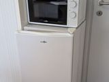 un petit réfrigérateur blanc surmonté d'un micro-ondes