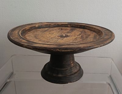 a small wooden bowl on a glass stand