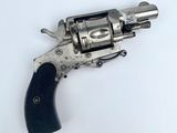 un revolver argenté avec une poignée noire sur une surface blanche