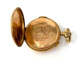 a gold pocket watch with a picture of a woman on it