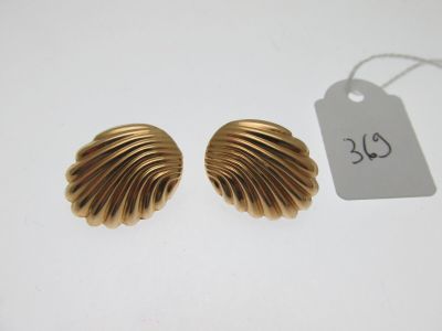 une paire de boucles d'oreilles en or en forme de coquillage posées sur un fond blanc