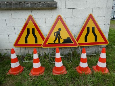 three road signs on the ground next to orange and white cones