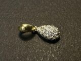 silver and gold plated pendant with a single stone on a black surface