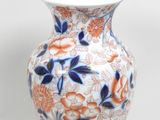un vase blanc orné de fleurs bleues et orange