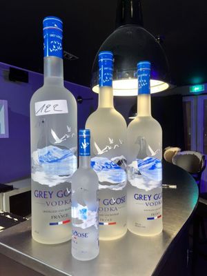 Trois bouteilles de vodka Grey Goose sont posées sur le comptoir d'un bar