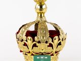 gold crown with a green plaque on top of it on a white surface