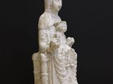 une vieille statue représentant une femme tenant un enfant dans ses bras, posée sur une table