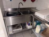 a stainless steel sink in a kitchen with white tile walls
